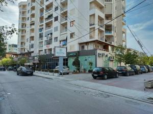 uma rua com carros estacionados em frente a um edifício alto em COASTAL apartment em Durrës