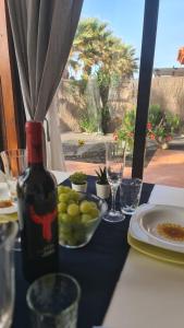 una mesa con una botella de vino y un tazón de uvas en Green Ocean House - Origo Mare, en Lajares 43 fotos más
