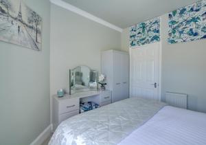 a white bedroom with a bed and a mirror at Sea Peeps in Hunstanton