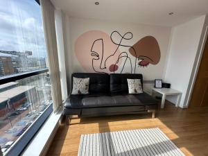 a living room with a black couch in front of a window at Cosy 1 bed next to SEC, OVO Hydro, Finnieston - Pass the Keys in Glasgow