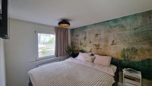 a bedroom with a bed with a painting on the wall at Woonboot Zus Zwaan in Alkmaar