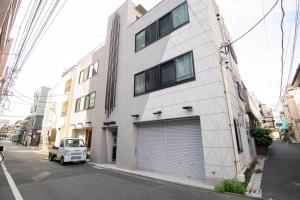 a white building with a garage door on a street at 浅草禅心居201室 浅草駅徒歩15分 2024年4月ニューオープン 43平米丸貸し切り ダブルベット2台と畳敷き布団2組 家庭式用品設備完備 in Tokyo
