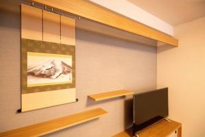 a room with a tv and a painting on the wall at 浅草禅心居201室 浅草駅徒歩15分 2024年4月ニューオープン 43平米丸貸し切り ダブルベット2台と畳敷き布団2組 家庭式用品設備完備 in Tokyo