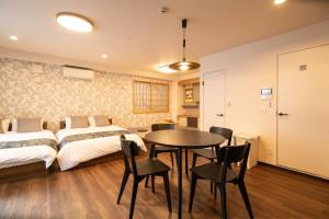 a bedroom with two beds and a table and chairs at 浅草禅心居201室 浅草駅徒歩15分 2024年4月ニューオープン 43平米丸貸し切り ダブルベット2台と畳敷き布団2組 家庭式用品設備完備 in Tokyo