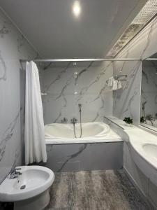Baño blanco con bañera y lavamanos en PORT INN Hotel en Astaná