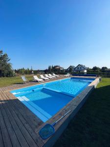 a swimming pool on a wooden deck with chairs around it at Ostrovia - pokoje nad morzem in Ostrowo