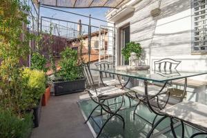 un patio con tavolo in vetro e sedie sul balcone. di Vivi la Magia di Looney Tunes, piazza navona a Roma