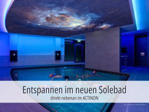 a swimming pool with two people in the water at Hotel Am Kurhaus mit erstem Ayurveda Center Sachsens - direkt am Gesundheitsbad ACTINON & Kurpark in Bad Schlema