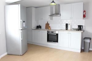 a kitchen with white cabinets and a refrigerator at Seashell Cottage in Llanddulas