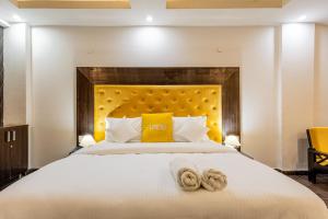 een slaapkamer met een groot wit bed met gele kussens bij Lime Tree Hotel Huda City Centre in Gurgaon