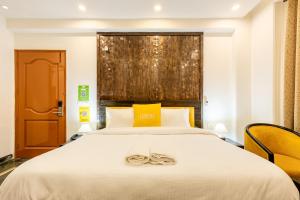 a bedroom with a large white bed and yellow chairs at Lime Tree Hotel Huda City Centre in Gurgaon