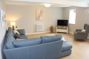 a living room with a blue couch and a tv at Seashell Cottage in Llanddulas