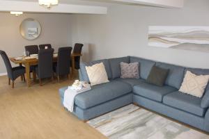 a living room with a blue couch and a table at Seashell Cottage in Llanddulas
