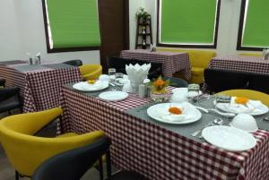 una sala da pranzo con tavoli e sedie gialle con piatti di Hotel Palm Royal Palace Bhimtal a Bhimtal