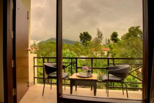 balcone con 2 sedie, tavolo e vista di Hotel Palm Royal Palace Bhimtal a Bhimtal