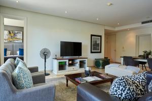 a living room with couches and a flat screen tv at Spacious Apartment Waterfront Fast WIFI in Cape Town