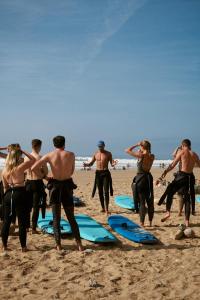 a group of people standing on a beach with surfboards at Olympe Surf & Yoga in Tamraght Ouzdar