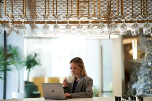 une femme assise à une table avec un ordinateur portable et une tasse de café dans l'établissement Ethereal White Resort Hotel & Spa, à Héraklion
