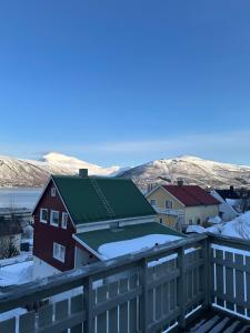 a red building with a green roof with snow on it at Koselig rom i leilighet in Tromsø