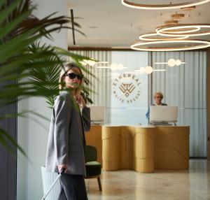 Una donna in piedi in un ufficio con una borsa in mano di Ethereal White Resort Hotel & Spa a Heraklion