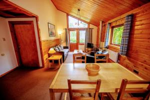 - un salon avec une table et des chaises en bois dans l'établissement Loch Insh Chalets Ltd, à Kincraig