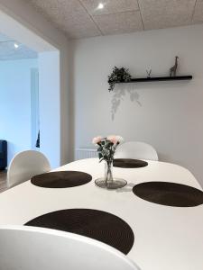 a white table with chairs and a vase of flowers on it at The Heart of Billund apartment in Billund