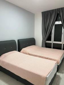dos camas sentadas una al lado de la otra en una habitación en Ipoh Town Anderson Haru Suite 7 paxs 2R2B, en Ipoh