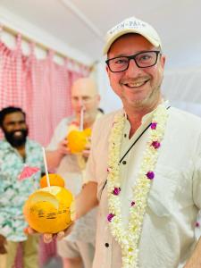 un hombre con gafas y un collar sosteniendo una bebida en Swiss kiss beach resort, en Uppuveli