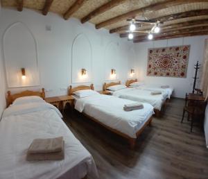 a group of four beds in a room at Sarrof Guest House in Bukhara