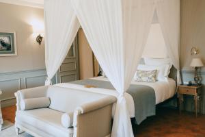 a bedroom with a white bed and a chair at Château de Fonscolombe in Le Puy-Sainte-Réparade