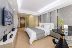 - une chambre avec un grand lit blanc et une télévision dans l'établissement Roomme私享家东山口地铁站公寓, à Canton
