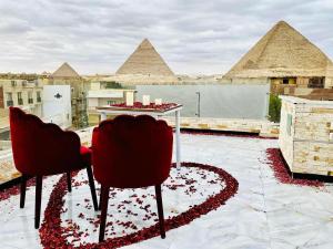 a table and chairs on a roof with pyramids at Locanda pyramids view in Cairo