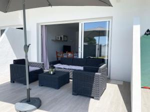 een patio met een bank, stoelen en een parasol bij Agoodplan Dehesa de El Palmar in Cádiz