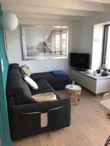 ein Wohnzimmer mit einem schwarzen Sofa und einem TV in der Unterkunft Ty Wrach in Landéda