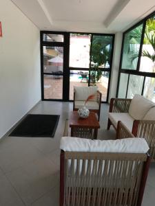 sala de estar con sillas, mesa y ventanas en Maraca Beach I - Flat 102, en Porto de Galinhas