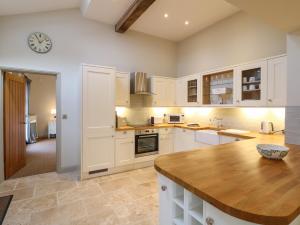 uma cozinha com armários brancos e um balcão de madeira em The Cottage em Yoxall