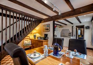 a dining room with a table and chairs and a staircase at Pitts Cottage in Brancaster