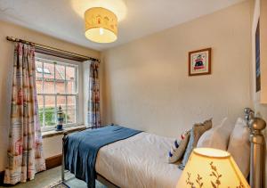 a bedroom with a bed and a window at Pitts Cottage in Brancaster