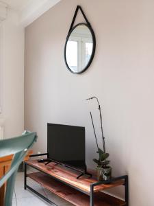 ein Wohnzimmer mit einem Spiegel und einem TV auf dem Tisch in der Unterkunft Le cocon d'Emile - Cosy et tout équipé in Nancy