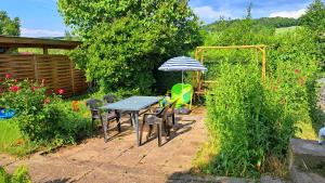 a table and chairs with an umbrella in a garden at Zum Jagdsteinblick in Bahretal