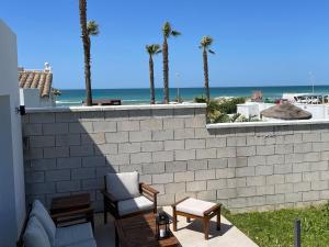 un patio con una pared de ladrillo, palmeras y el océano en Agoodplan Aitana Playa El Palmar, en El Palmar