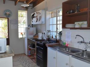 uma cozinha com um lavatório e um fogão forno superior em Gentle Presence Cottages em Clarens