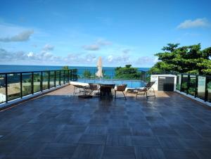 a patio with a table and chairs and the ocean at Maraca Beach I - Flat 102 in Porto De Galinhas