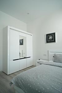敖德萨Апартаменты в Аркадии - Arcadia Sky Apartments的一间白色卧室,配有一张床和一个梳妆台