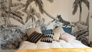 un canapé avec des oreillers et une fresque murale de palmiers dans l'établissement Villa Ty Amor, à Guissény
