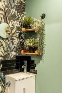 La salle de bains est pourvue d'un lavabo et d'une étagère avec des plantes. dans l'établissement Villa Ty Amor, à Guissény