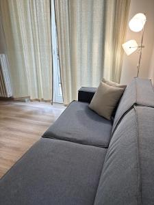 Casa Scaletta Santa Lucia في بيرغامو: أريكة رمادية في غرفة المعيشة مع مصباح