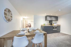 a kitchen with a wooden table and white chairs at Basement Bliss Hideaway in Bradford