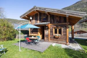 una baita di tronchi con tavolo e ombrellone blu di Chalet le petit bornand a Les Houches