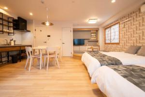 a bedroom with two beds and a table and a kitchen at 浅草駅徒歩15分 2024年4月ニューオープン 2020年10月新築マンション 2023年12月リフォーム 43平米丸貸し切り ダブルベット2台と畳敷き布団2組 家庭式用品設備完備 202室 in Tokyo